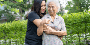 two women in a hug in front of greenery.